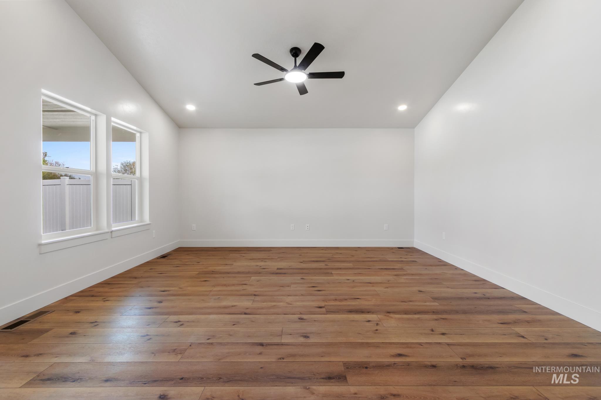 321 North 11th Street Parma, ID 83660 - Photo 11 of 36 Spacious room featuring wood-finish flooring, white walls, and a black ceiling fan with integrated lighting
