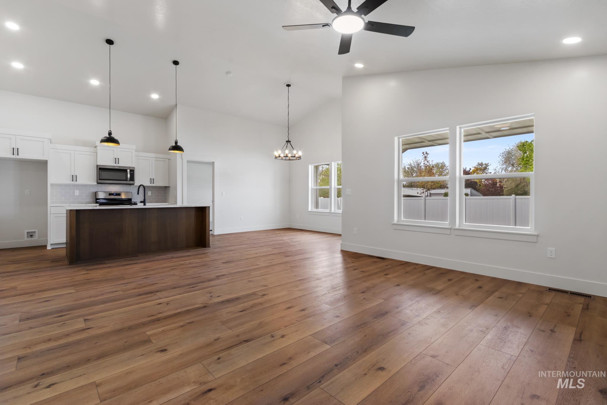 321 North 11th Street Parma, ID 83660 - Photo 13 of 36 Open-concept interior featuring wood-finish flooring, vaulted ceilings, and a kitchen with white cabinetry and an island