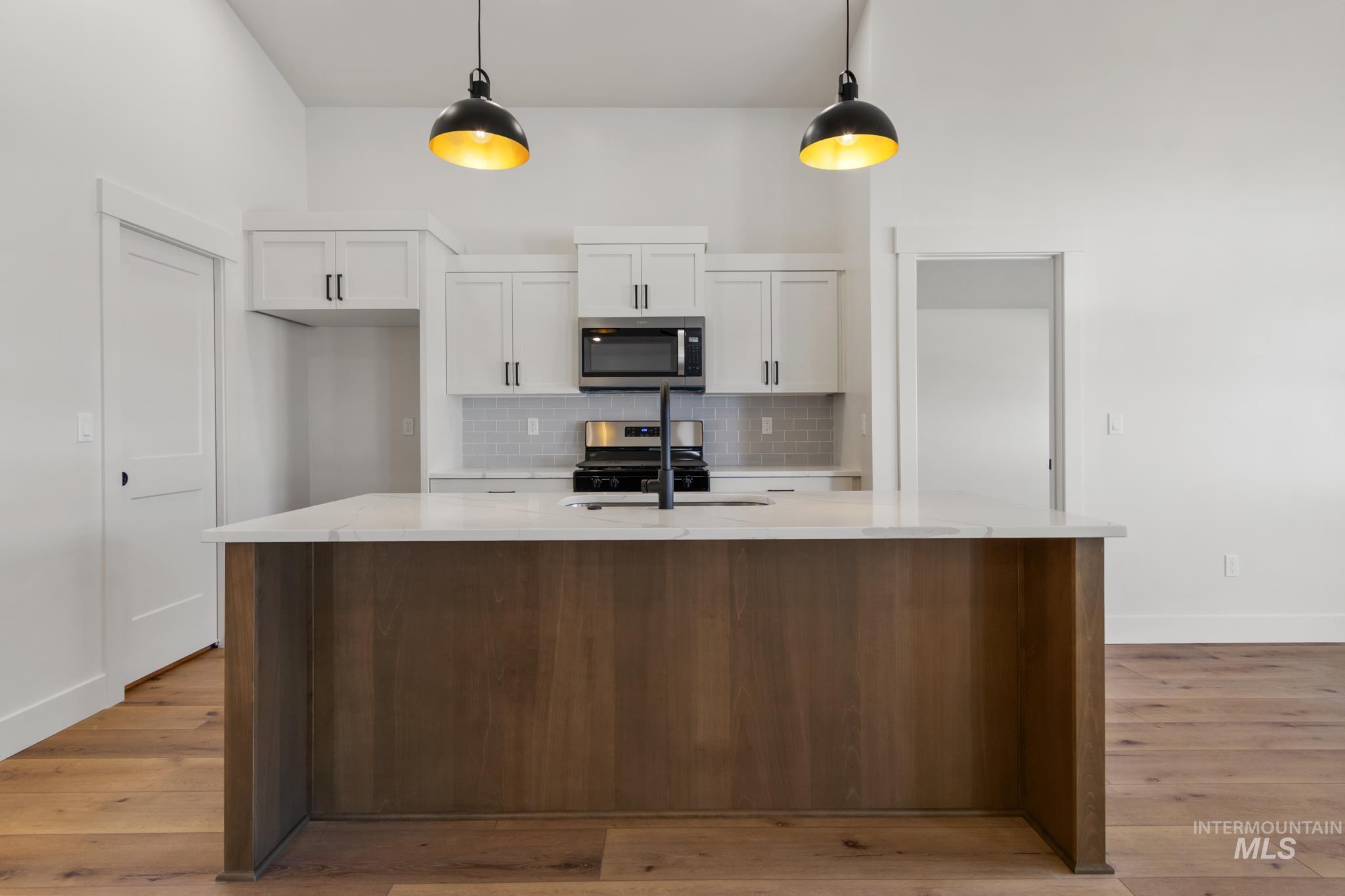321 North 11th Street Parma, ID 83660 - Photo 14 of 36 Kitchen island featuring a light-toned countertop and wood-finish base, complementing the wide plank wood-finish flooring