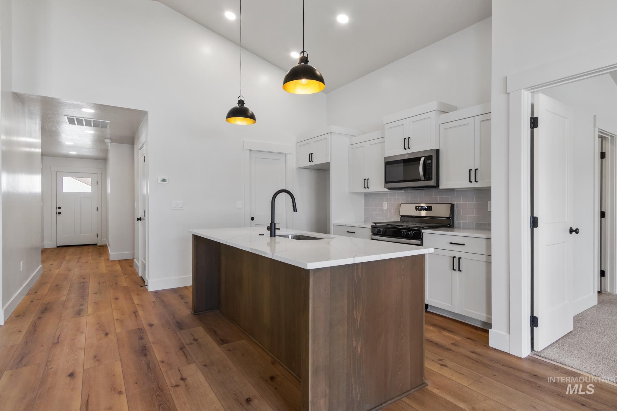 321 North 11th Street Parma, ID 83660 - Photo 15 of 36 Open-concept kitchen featuring an oversized wood-finish island with a white countertop, matte black gooseneck faucet, and integrated sink