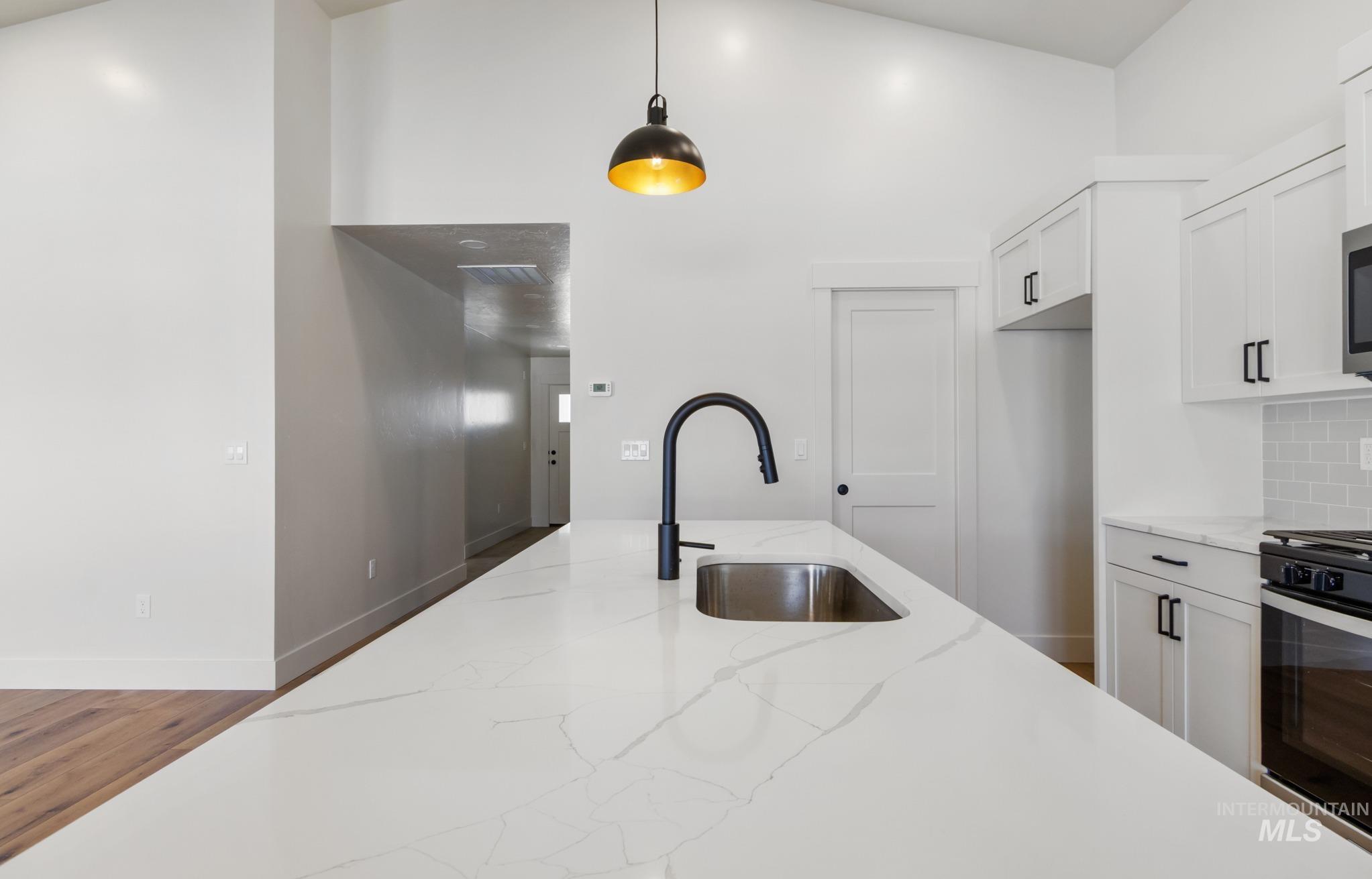 321 North 11th Street Parma, ID 83660 - Photo 16 of 36 Kitchen island featuring a stainless steel undermount sink and a matte black gooseneck faucet