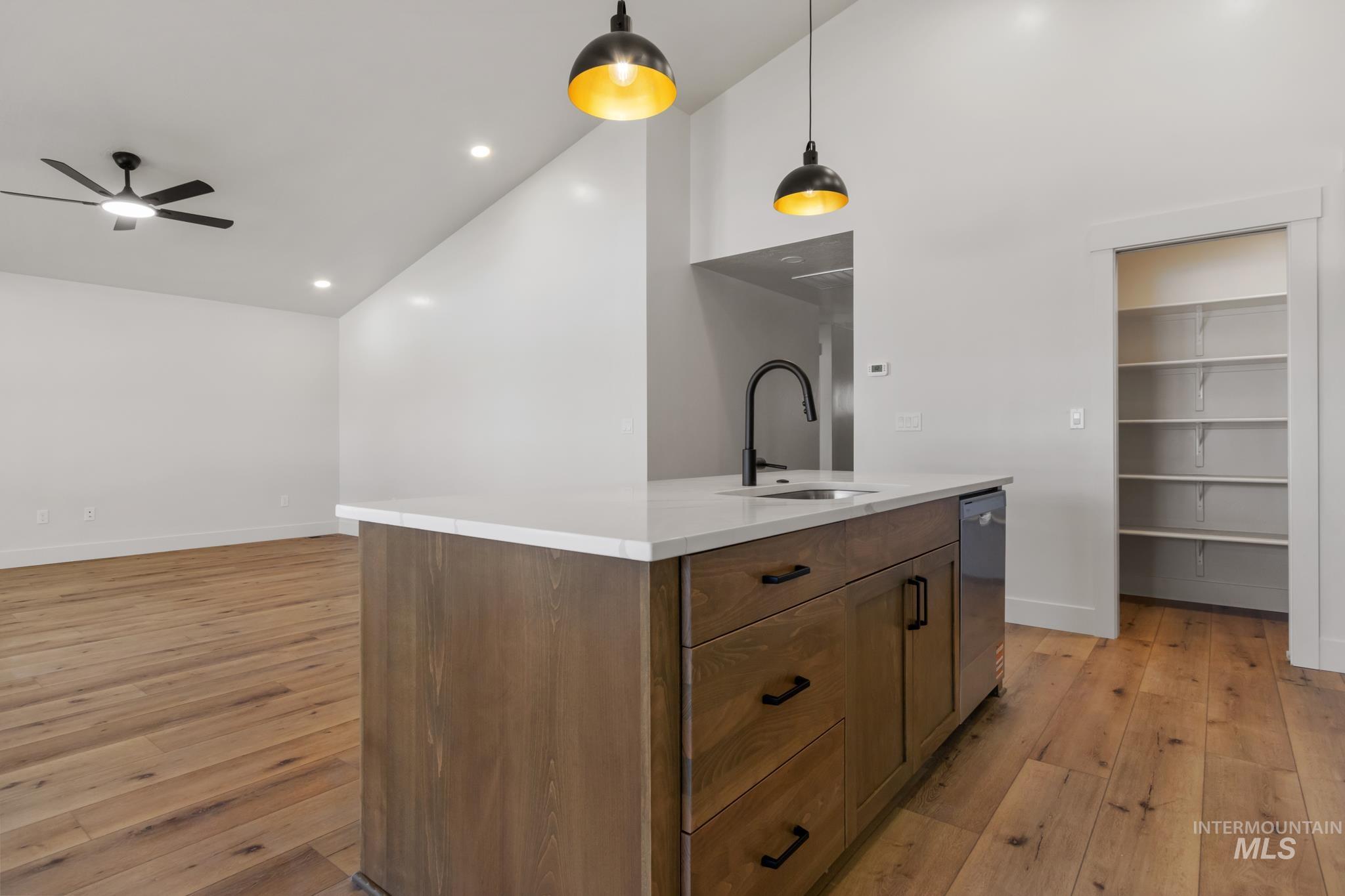 321 North 11th Street Parma, ID 83660 - Photo 17 of 36 Kitchen island featuring a white countertop, an integrated sink with a matte black gooseneck faucet, and wood-finish cabinetry