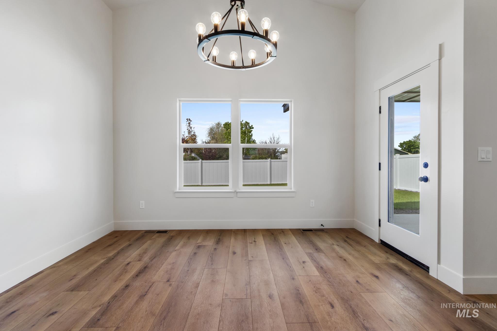 321 North 11th Street Parma, ID 83660 - Photo 20 of 36 Vaulted ceiling interior space featuring wood-finish flooring, a contemporary circular chandelier, dual pane windows, and a glass-paneled exterior door