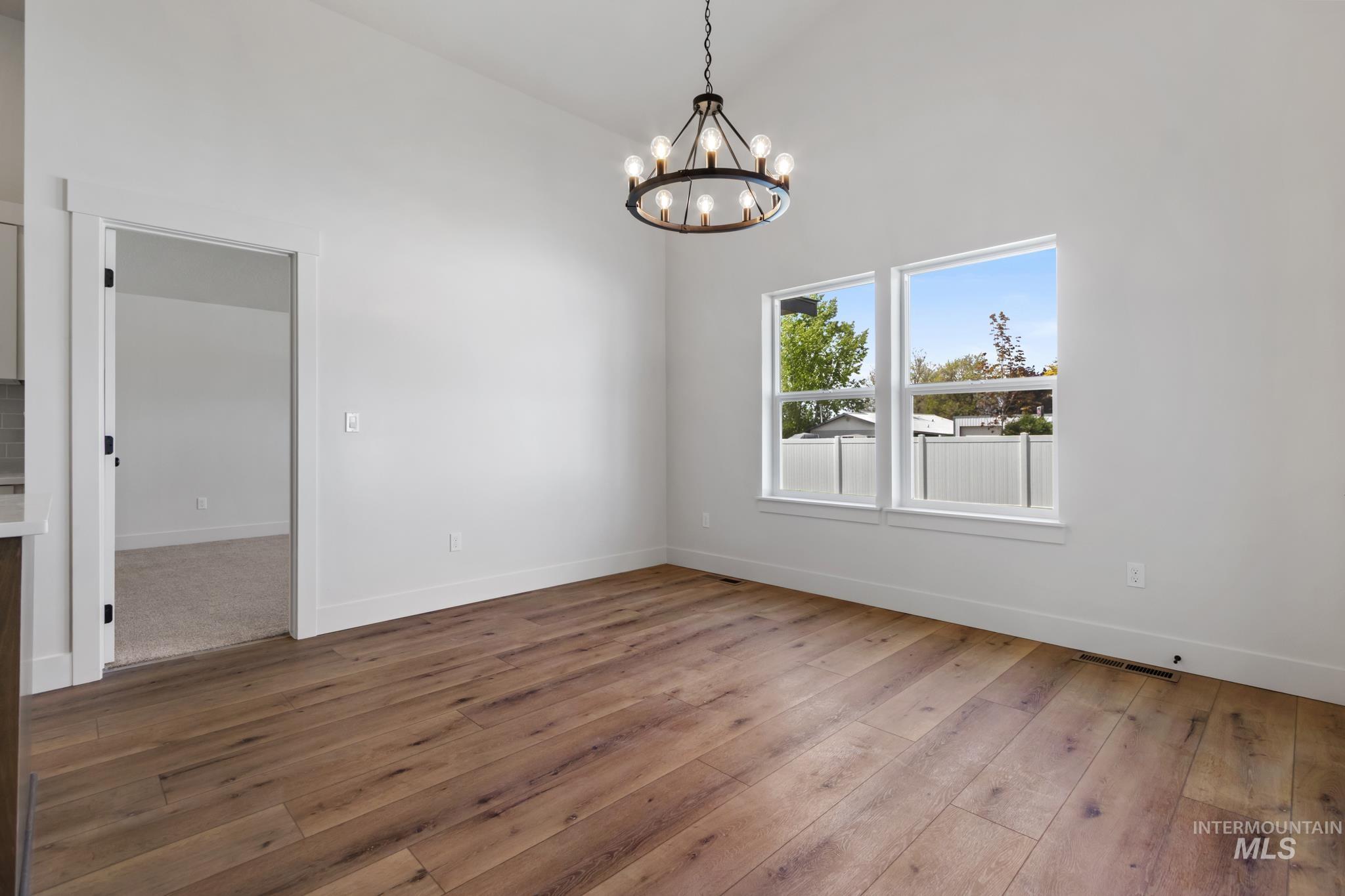 321 North 11th Street Parma, ID 83660 - Photo 21 of 36 Open-concept room featuring wood-finish flooring, vaulted ceilings, and a contemporary chandelier