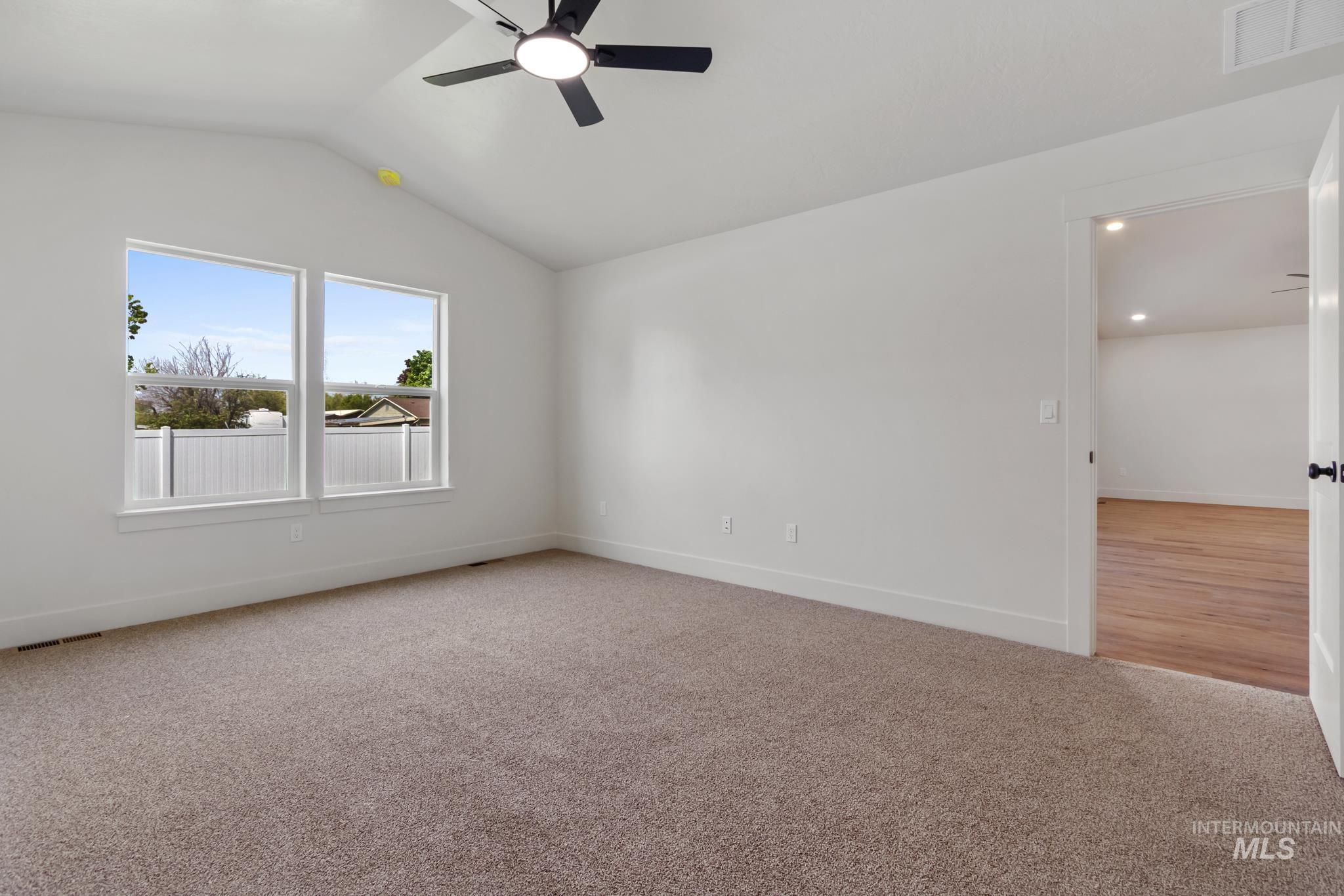 321 North 11th Street Parma, ID 83660 - Photo 22 of 36 Spacious room featuring vaulted ceilings, dual windows, a ceiling fan, and plush carpet flooring