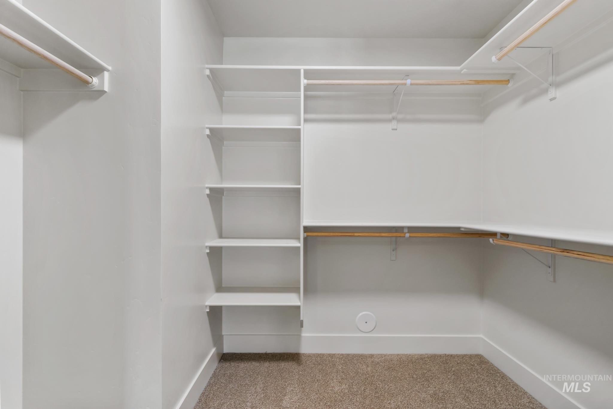 321 North 11th Street Parma, ID 83660 - Photo 28 of 36 Walk-in closet featuring white built-in shelving, multiple hanging rods, white baseboards, and neutral-toned carpeting