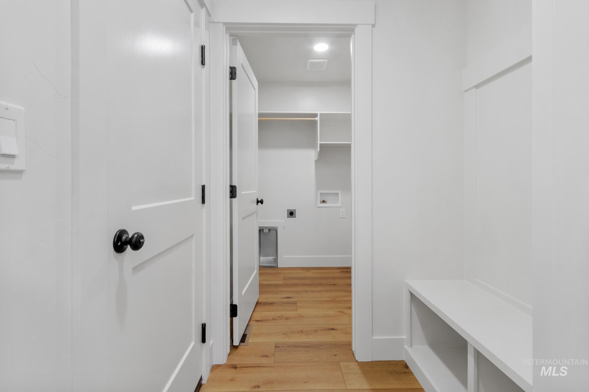 321 North 11th Street Parma, ID 83660 - Photo 31 of 36 Hallway featuring white paneled doors with matte black hardware, wood-finish flooring, and a built-in bench with storage cubbies