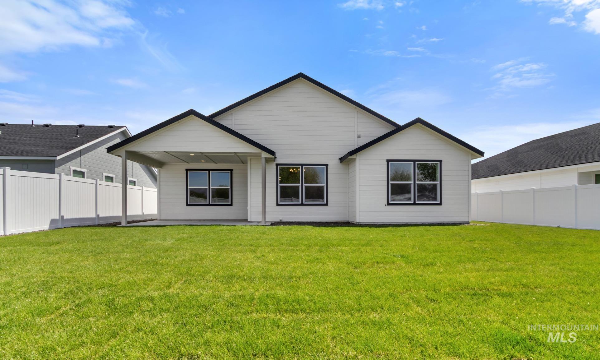 321 North 11th Street Parma, ID 83660 - Photo 32 of 36 Expansive backyard featuring a manicured lawn, a covered patio, white siding, black-framed windows, and a black shingle roof