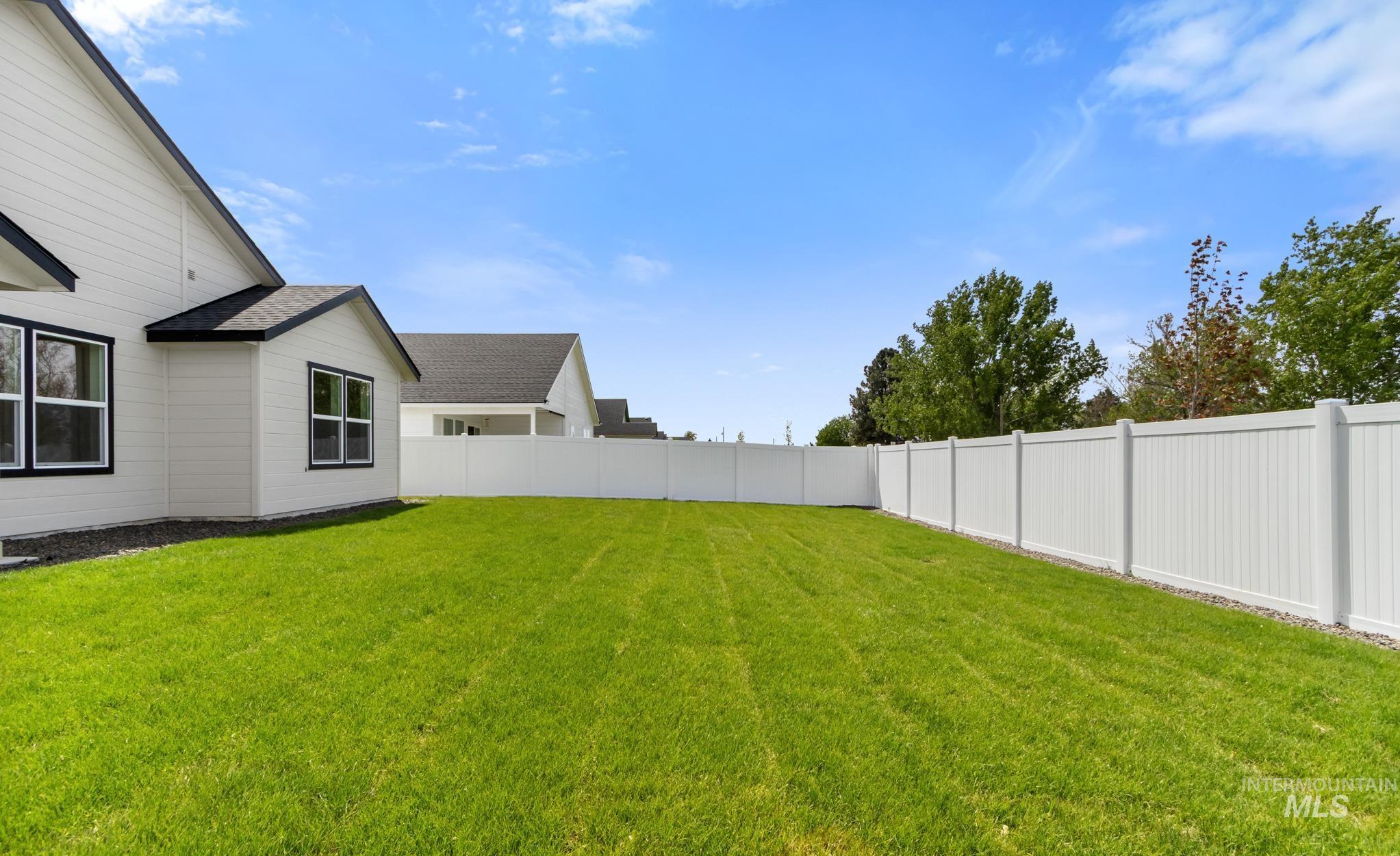 321 North 11th Street Parma, ID 83660 - Photo 33 of 36 Expansive backyard with vibrant green lawn, framed by a white privacy fence