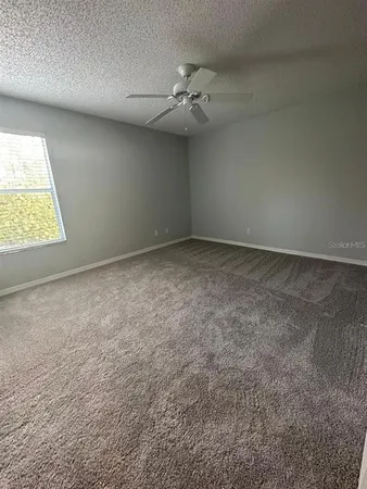 an empty room with a ceiling fan and window