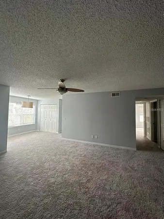 en empty room with windows and ceiling fan