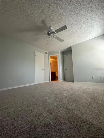 a view of an empty room with a ceiling fan and window