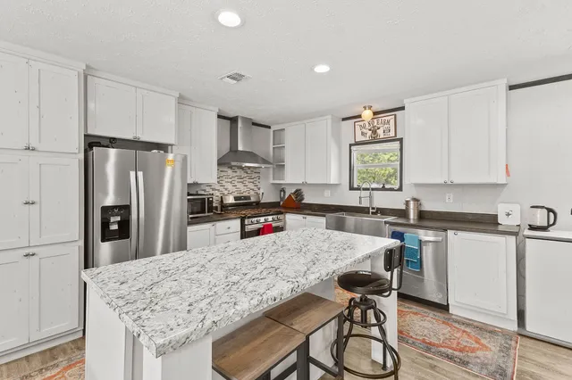 a kitchen with stainless steel appliances granite countertop a table chairs sink refrigerator and microwave