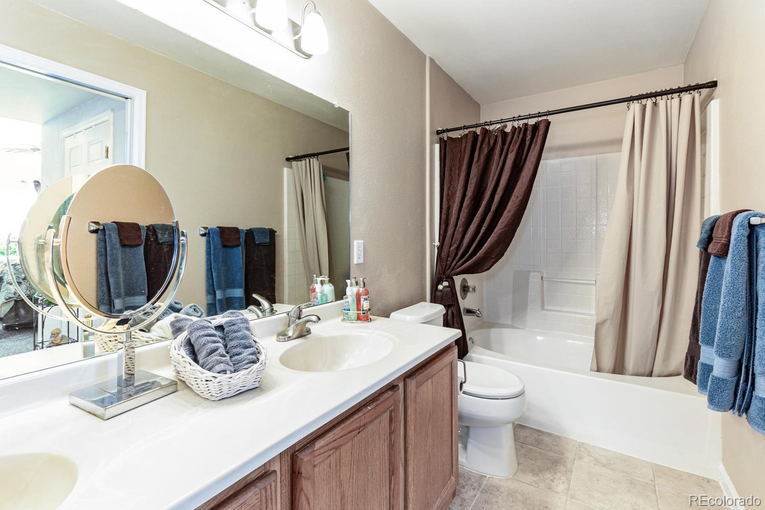 8425 Pebble Creek Way, Unit 104 Highlands Ranch, CO 80126 - Photo 12 of 16 a bathroom with a double vanity sink toilet and shower