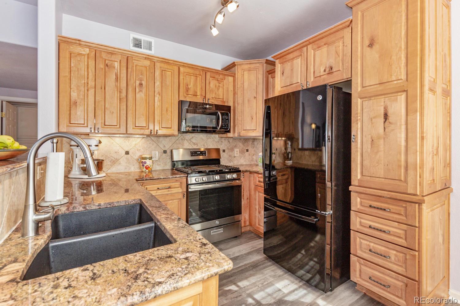 8425 Pebble Creek Way, Unit 104 Highlands Ranch, CO 80126 - Photo 4 of 16 a kitchen with stainless steel appliances granite countertop a refrigerator stove and sink