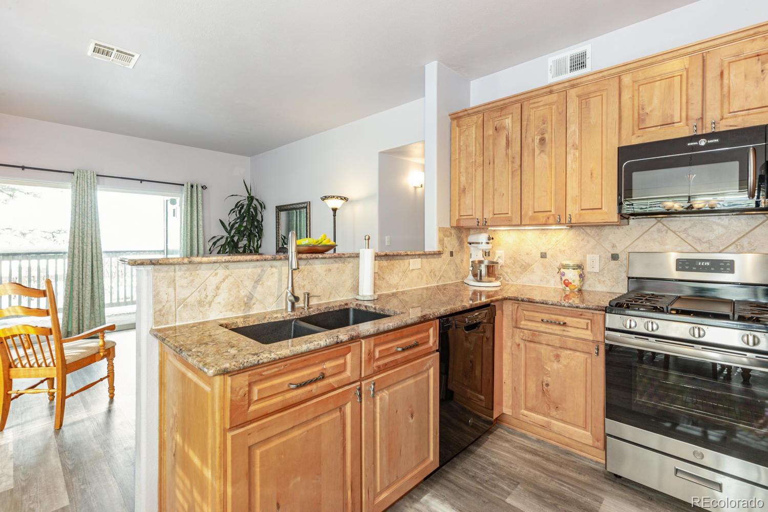 8425 Pebble Creek Way, Unit 104 Highlands Ranch, CO 80126 - Photo 5 of 16 a kitchen with granite countertop a sink stove and cabinets