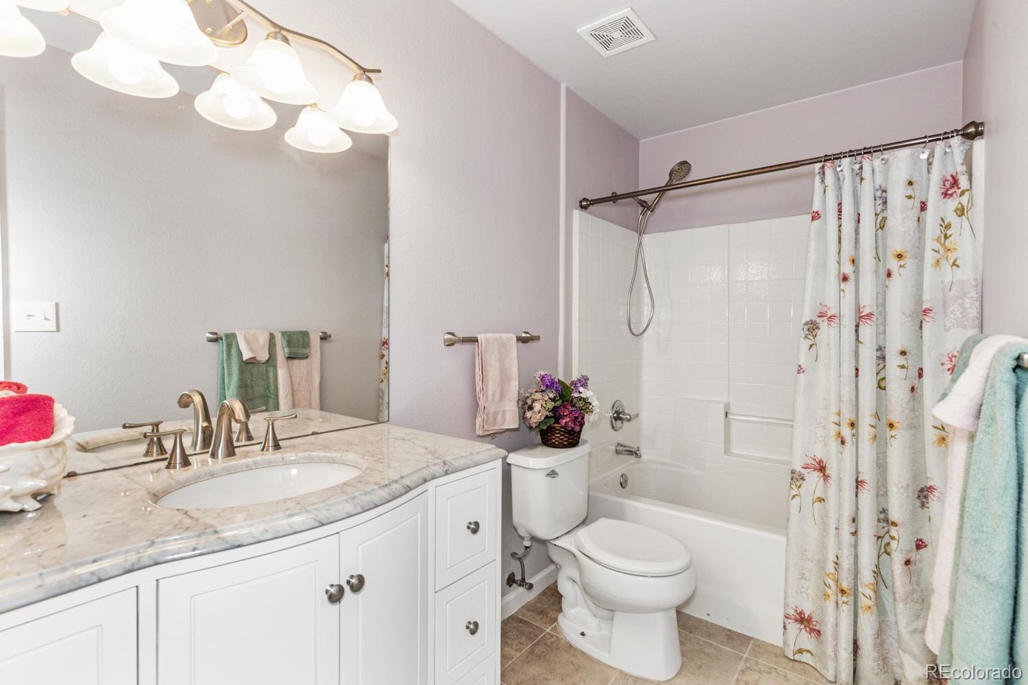 8425 Pebble Creek Way, Unit 104 Highlands Ranch, CO 80126 - Photo 8 of 16 a bathroom with a shower sink vanity mirror and toilet