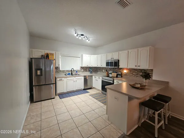 a kitchen with a sink stainless steel appliances and white cabinets