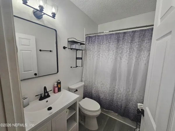 a bathroom with a sink a toilet and shower curtain