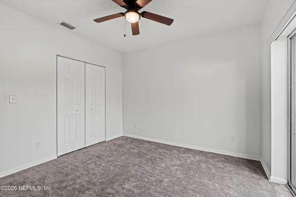 an empty room with a ceiling fan and a window