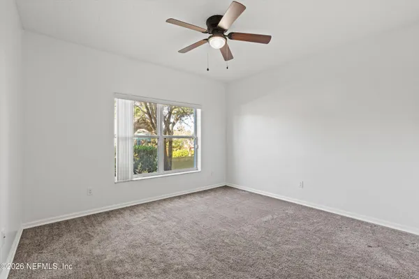 an empty room with windows and fan