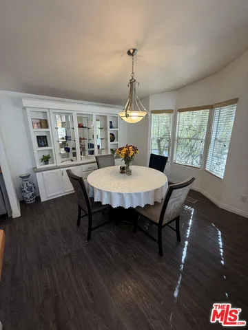a dining room with wooden floor a chandelier a wooden table and chairs