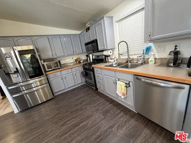 a kitchen with granite countertop a stove top oven a sink dishwasher and a microwave with wooden floor