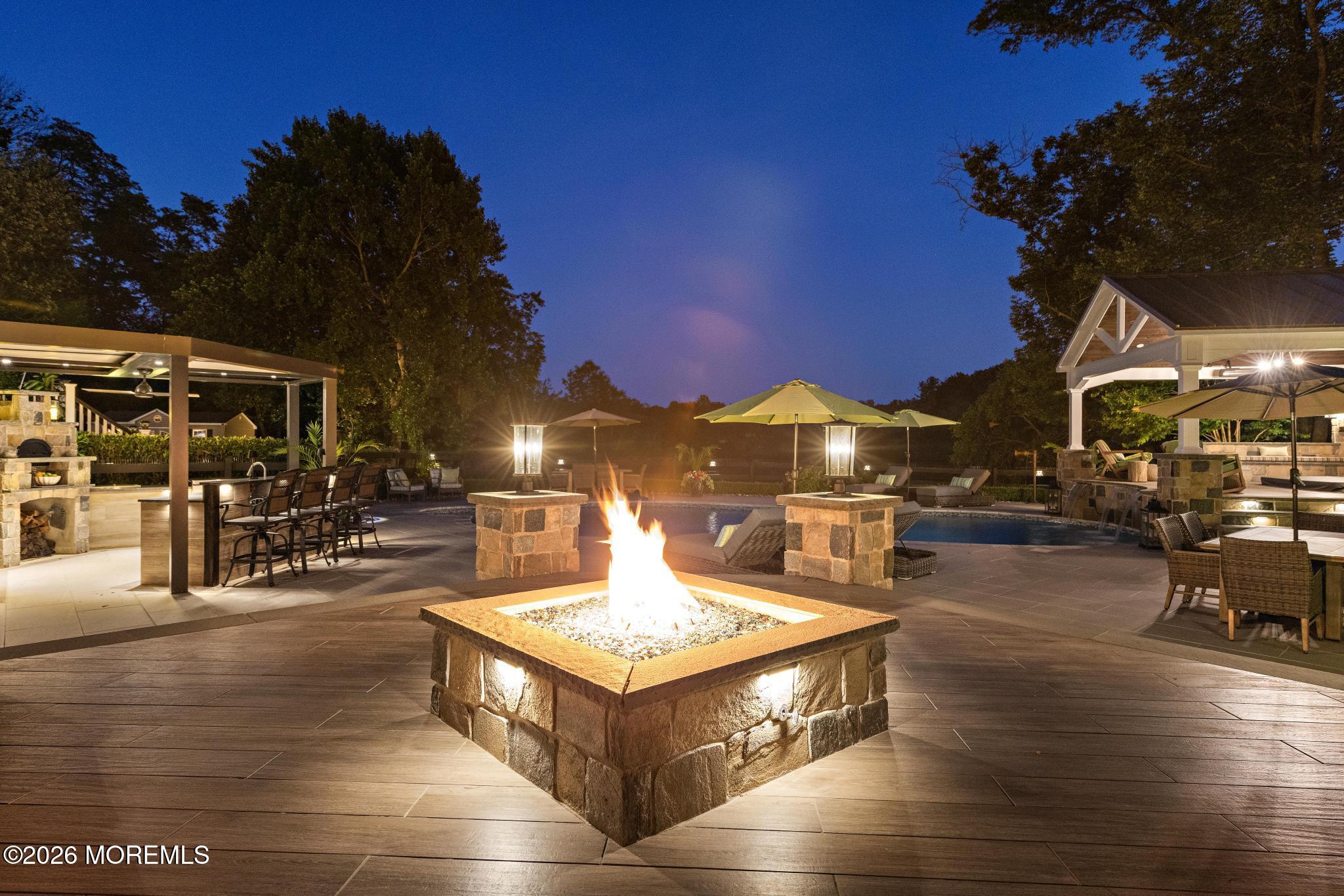 57 Beaver Dam Road Colts Neck, NJ 07722 - Photo 54 of 79 a view of a patio with dining table and chairs with a fire pit