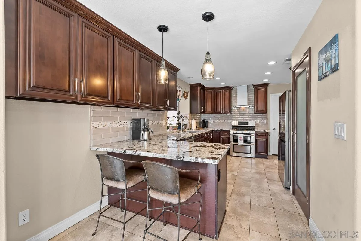 10109 Country Scenes Court Santee, CA 92071 - Photo 12 of 43 a kitchen with stainless steel appliances granite countertop a sink a stove a refrigerator cabinets a dining table and chairs
