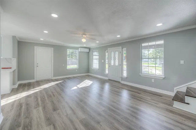 a view of empty room with wooden floor and fan