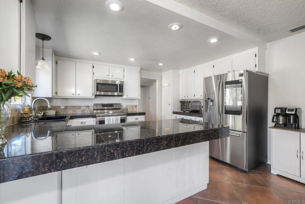 554 Taylor Street Vista, CA 92084 - Photo 18 of 51 a kitchen with a refrigerator a sink a stove a microwave and cabinets