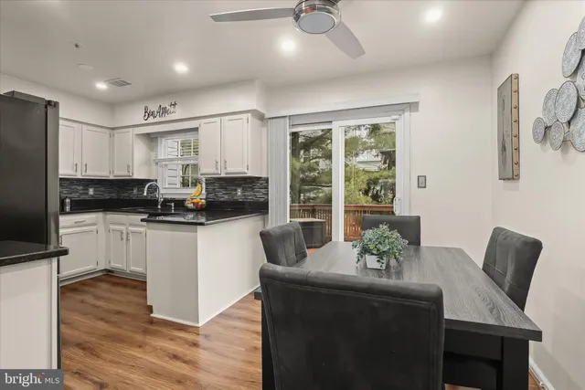 a kitchen with stainless steel appliances granite countertop a stove a refrigerator a sink a dining table and chairs with wooden floor