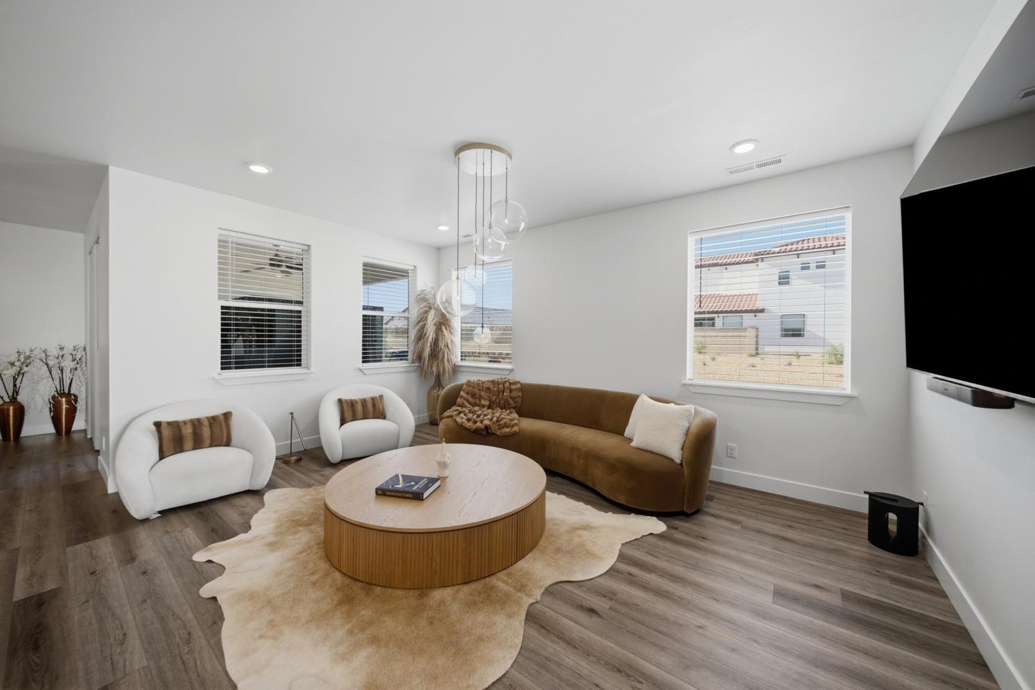 6144 Red Sand Lane St. George, UT 84790 - Photo 4 of 19 Open and airy, the great room centers on a curved cognac sofa and a pair of plush swivel chairs arranged atop a soft cowhide rug. A dramatic bubble-glass pendant cascades from the ceiling, while the mounted flat-screen and oversized windows strike a balance between comfort and cutting-edge style.