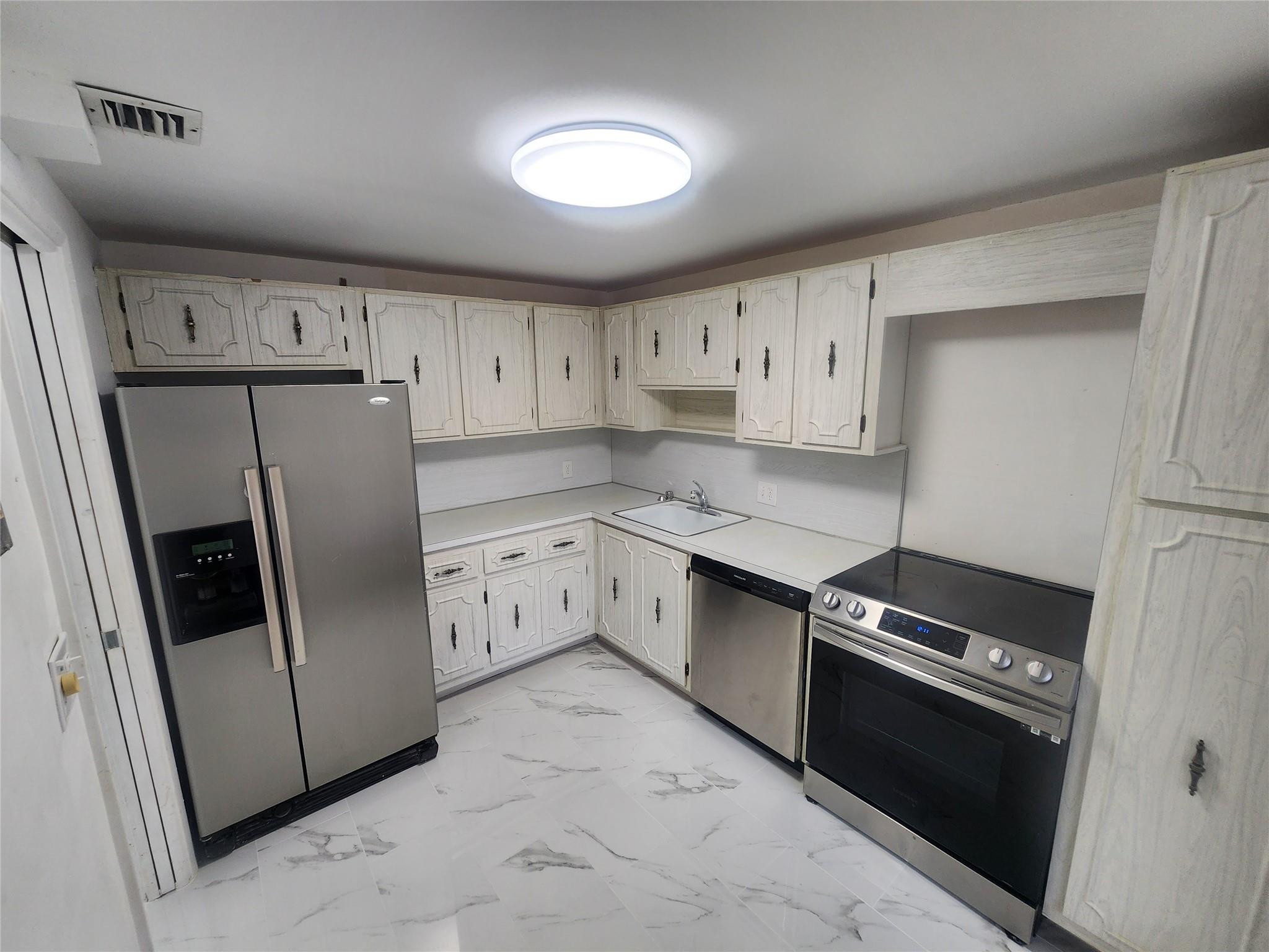 3051 North Course Drive Pompano Beach, FL 33069 - Photo 3 of 13 a kitchen with white cabinets and white appliances