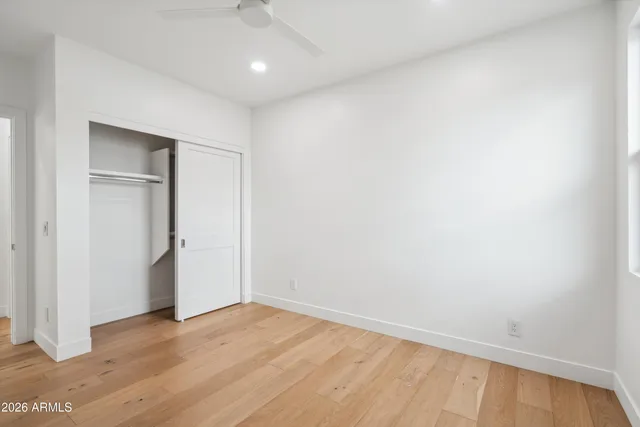 a view of empty room with wooden floor and fan