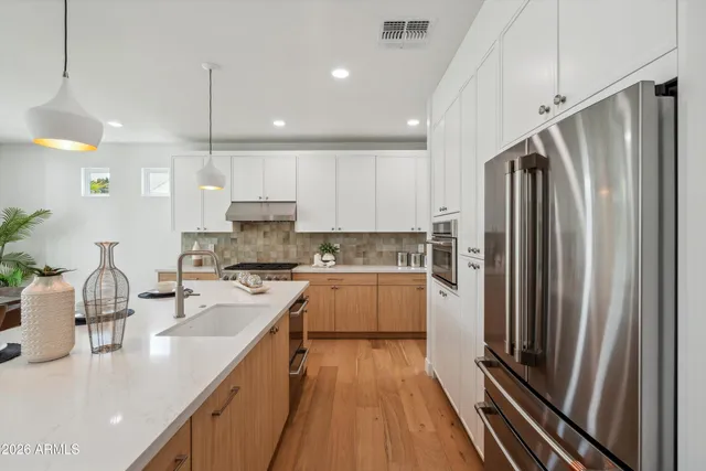 a kitchen with kitchen island a counter top space a sink stainless steel appliances and cabinets