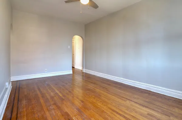 a view of a room with wooden floor and a ceiling fan