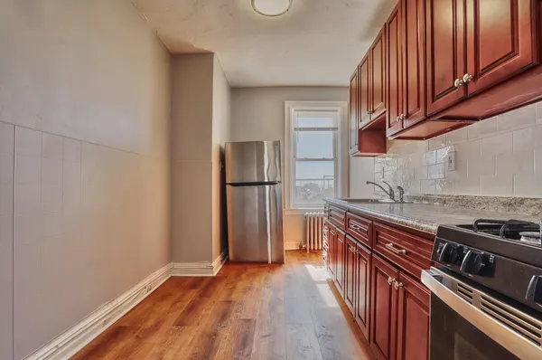 a kitchen with stainless steel appliances granite countertop a refrigerator a stove and a wooden floors