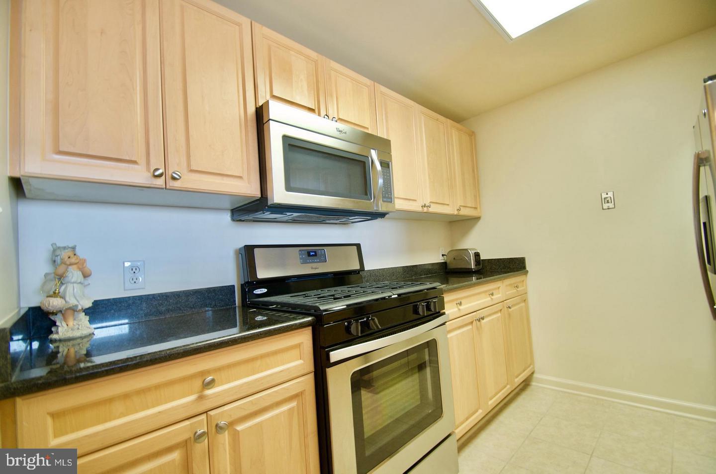2726 Gallows Road, Unit 917 Vienna, VA 22180 - Photo 7 of 25 a kitchen with stainless steel appliances granite countertop white cabinets and a stove top oven