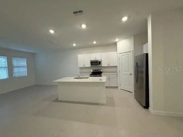 a view of kitchen with stainless steel appliances refrigerator stove microwave and cabinets