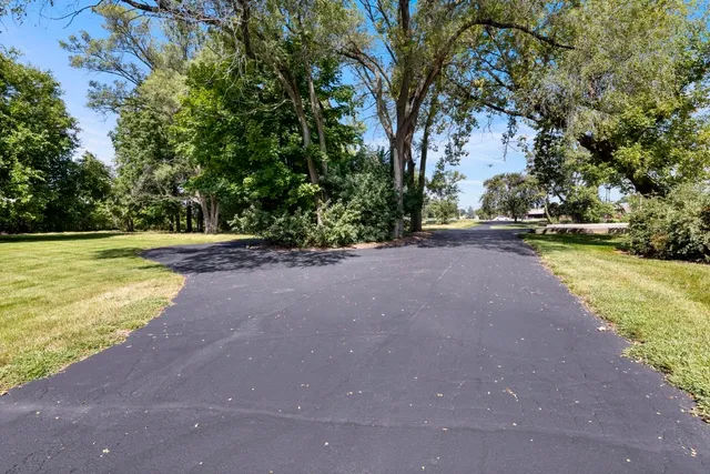an aerial view of residential house with outdoor space and trees all around