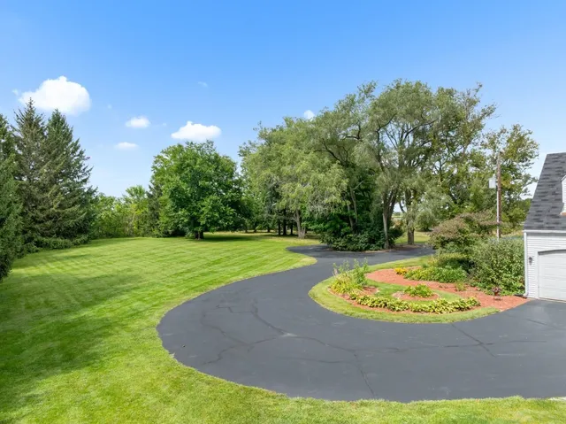 an aerial view of residential house with outdoor space and trees all around