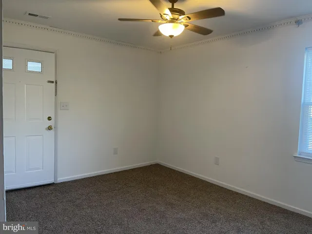 an empty room with a chandelier fan and a bathroom