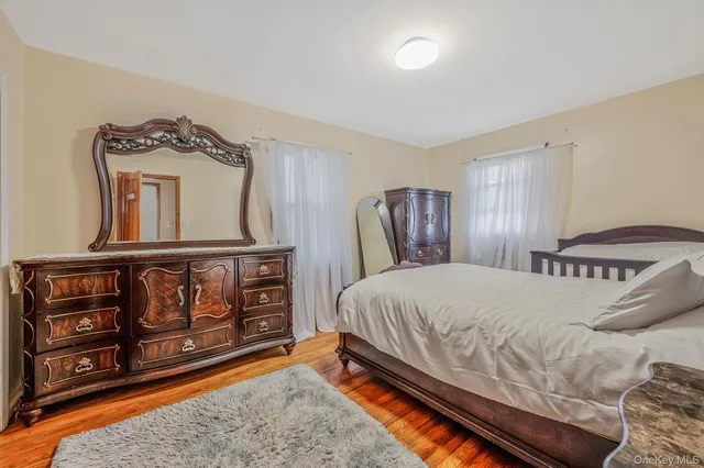 a bedroom with a bed a dresser with wooden floor
