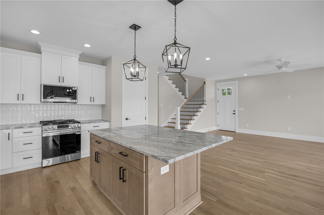 1230 Melton Road, Unit 216 West Union, SC 29696 - Photo 7 of 49 Gleaming hardwood floors extend through this open-concept space, highlighting the kitchen's central island and modern appliances.