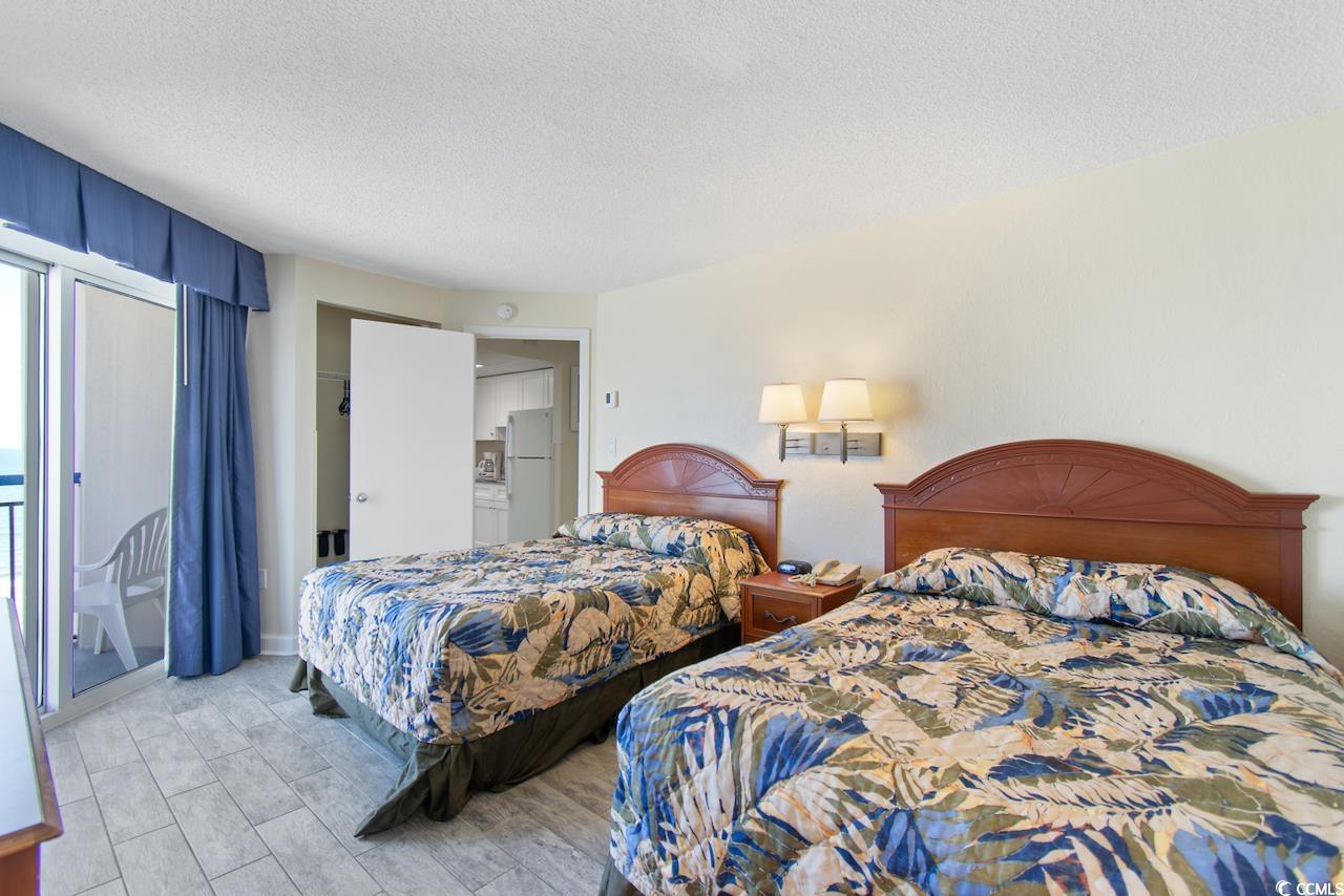 2300 North Ocean Boulevard, Unit 830 Myrtle Beach, SC 29577 - Photo 18 of 33 Bedroom with a textured ceiling, freestanding refrigerator, access to exterior, and light wood-style floors