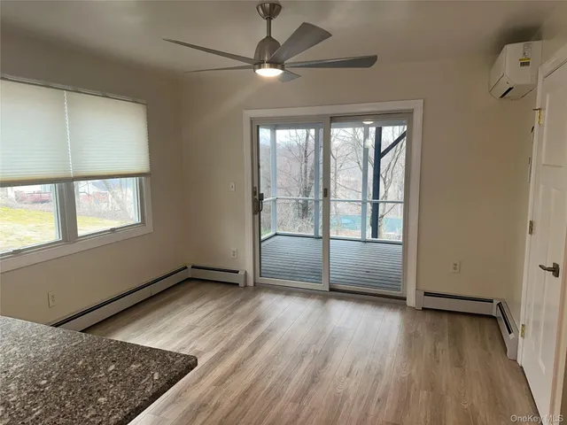 an empty room with wooden floor fan and windows