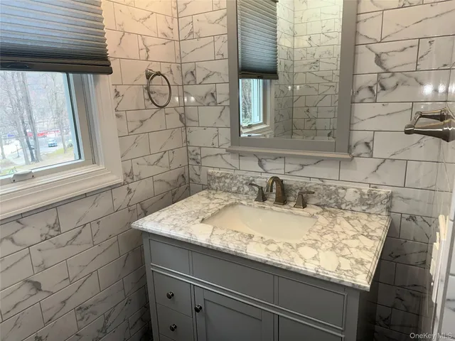 a bathroom with a granite countertop sink and a window
