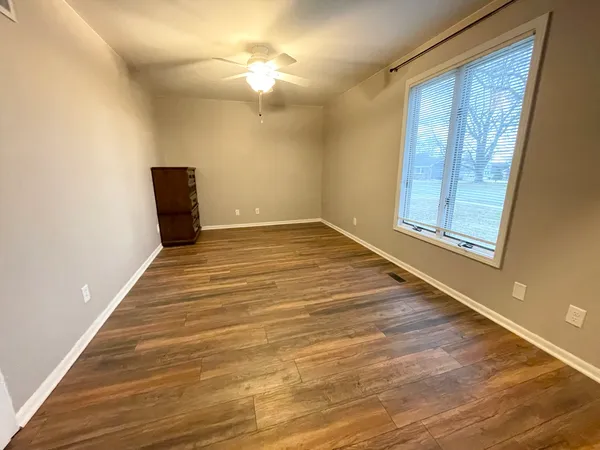 a view of an empty room with a chandelier fan and wooden floor