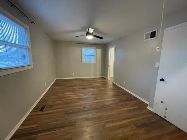 a view of an empty room with wooden floor and a window
